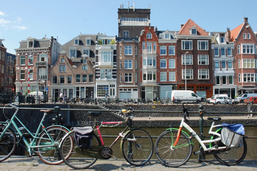bicycles next to a canal, buildings in the background