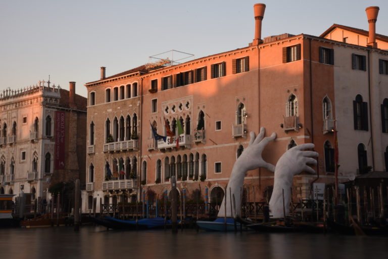 Palazzo by the Canal Grande with big hand sculptures coming out of water